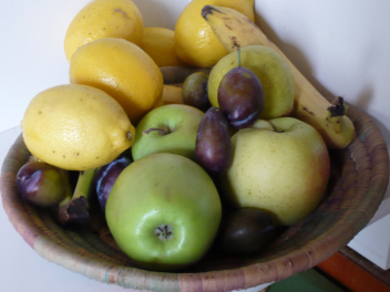 Plat de fruits avec pruneaux, pommes, citrons et bananes