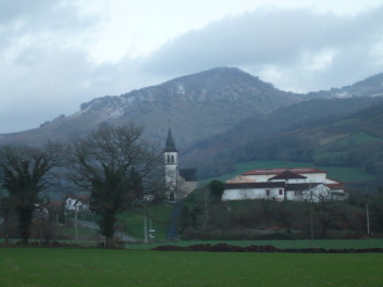jÉglise Saint-Jean-Porte-Latine à Bussunarits-Sarrasquette (64) avec montagnes un peu enneigées en arrière-plan